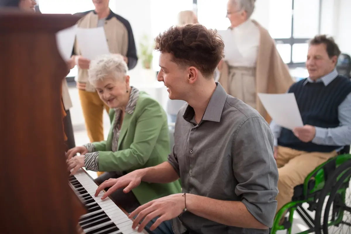 Senior Living Bozeman MT Guide for Families Senior woman playing piano with a teacher, reflecting senior living in Bozeman MT and the active community life families want for a loved one