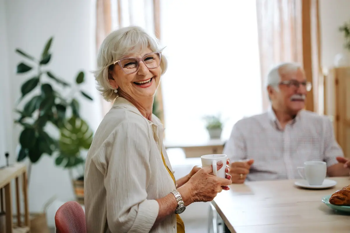 Assisted Living in Bozeman: smiling senior woman enjoys coffee in bright dining room